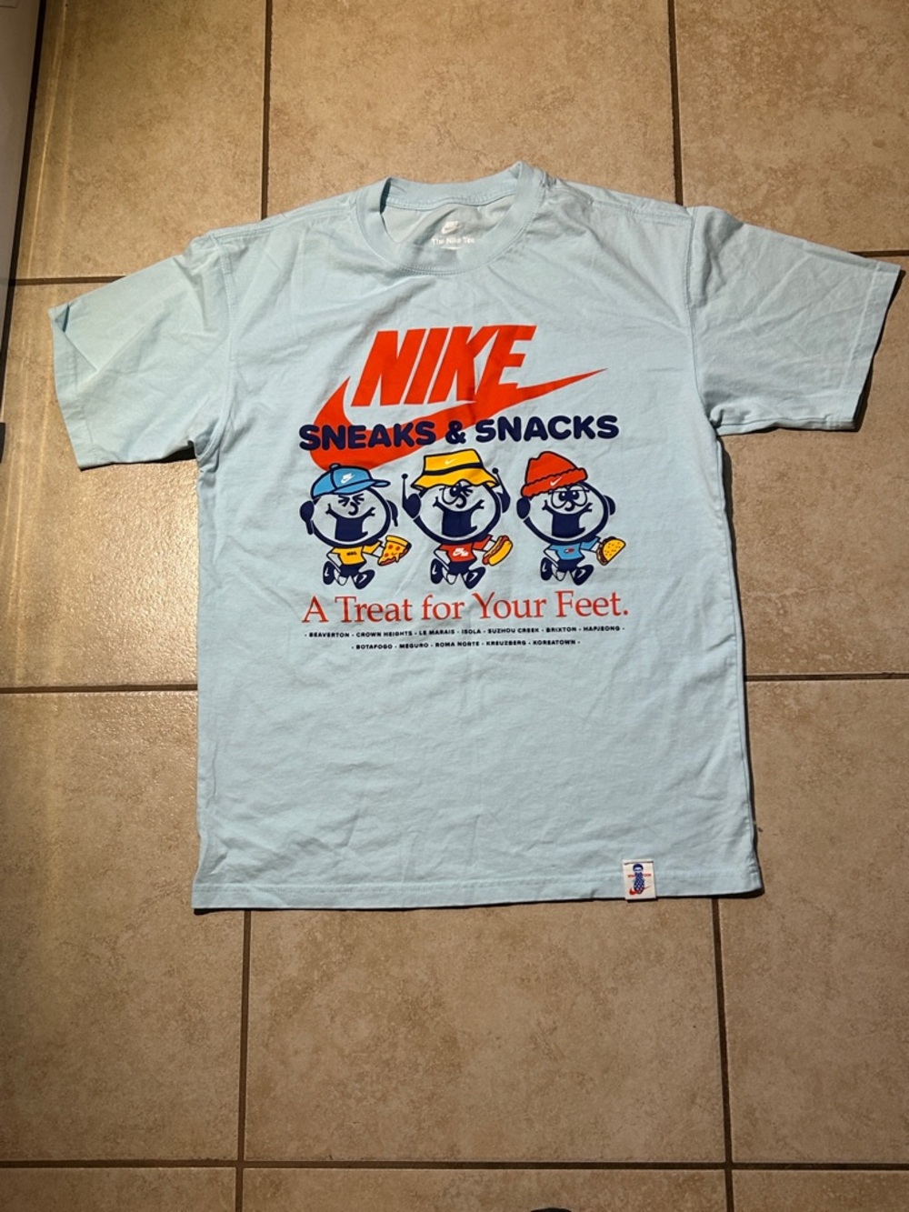 Nike Light Blue 'Sneaks & Snacks' Graphic Tee with Orange Logo